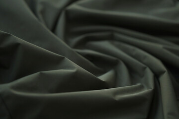 Texture of Dark green military uniform textile cloth with folds