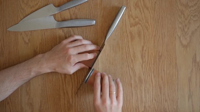Knife sharpening in progress with a rolling knife sharpener. A man flips the tool to switch from coarse grinding to the fine honing grit for a perfect blade edge. Includes original audio.