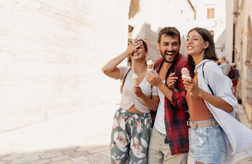 Three young tourists having fun and eating ice cream while traveling