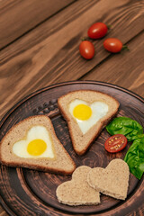 delight in festive breakfast heart-shaped eggs fried within slices of bread. accompanied by cherry tomatoes and fresh greens, this dish radiates joy and creativity. vertical. close up.
