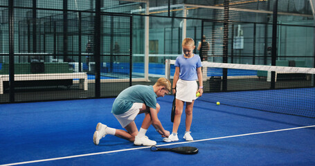 Padel, sports and children tie shoes on court for workout, exercise and training together. Tennis...