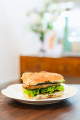 Foccacia bread sandwich with sausage and vegetableon table in cafe.