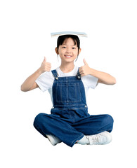 A cheerful child balancing a book on her head while sitting cross-legged, giving thumbs up. The...