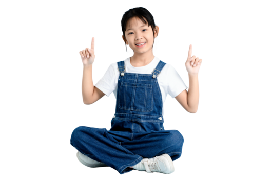 A cheerful young girl sitting with legs crossed and pointing upwards on PNG 