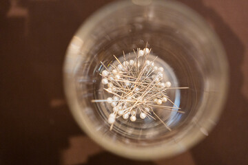 A pile of white glass head pins used for sewing, needlework and other projects.
