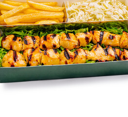 Grilled chicken skewers served with fries and shredded cabbage