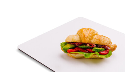 Fresh croissant sandwich with vegetables on a white plate