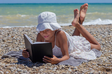 Child absorbed in a book on a rocky beach