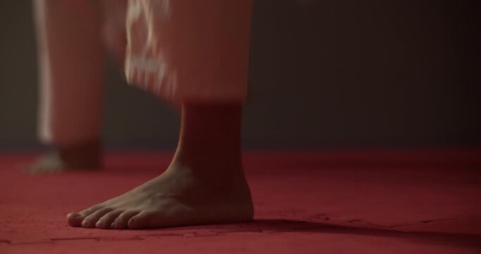 Bare feet of karateka train kick on mat of martial arts club