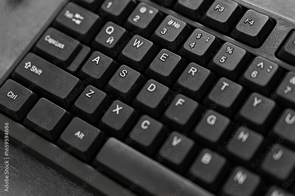 Fototapete a black computer keyboard with white sticky key designations in english in close-up with an ink to r