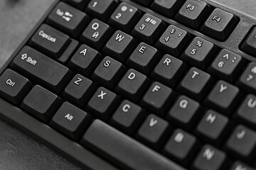 A black computer keyboard with white sticky key designations in English in close-up with an ink to...