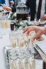 Guest hand picking glass of champagne at wedding reception cocktail party with drinks and appetizers, elegant celebration detail of festive atmosphere.