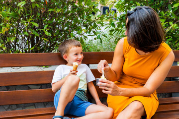 Mother and son sharing ice cream on park bench