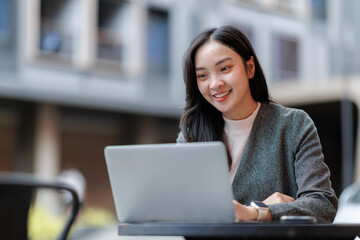 Smiling businesswoman working on laptop in outdoor cafe