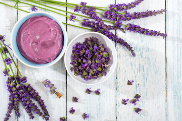 cosmetic cream and purple lavender flowers on white wooden, directly above