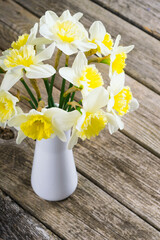white daffodils at china vase on old weathered wood table