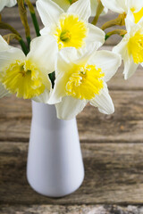 white daffodils at china vase on old weathered wood table