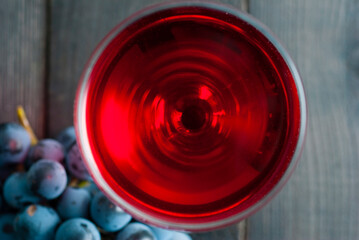 glass of red wine and grapes on black wood table background