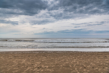 Sandy beach on the North Sea coast of the Netherlands under cloudy sky