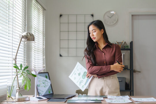 Businesswoman analyzing green energy investments in modern office