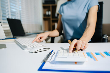 Women counting coins on calculator taking from the piggy bank. hand holding pen working on calculator to calculate on desk about cost at home office.