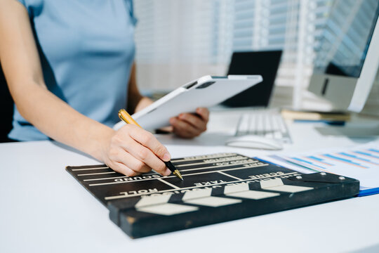 Creative woman using clapperboard in modern office studio, perfect for film production, video content, and cinematic storytelling concepts.