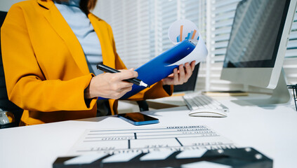 Creative female filmmaker working with tablet, clapperboard, and laptop in modern studio office....