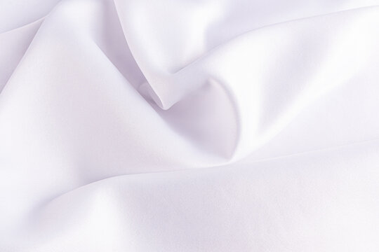 Satin fabric background in soft white folds and texture