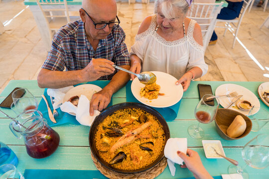 Seniors enjoying Spanish cuisine at a seaside restaurant
