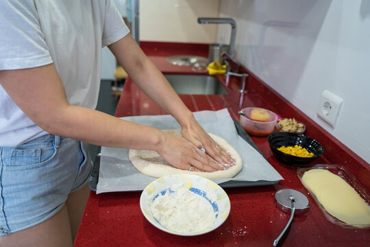 Pizza preparation by hand on red kitchen countertop
