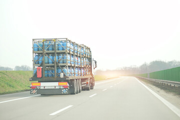 Industrial Truck Carrying Stacked Blue Gas Cylinders in Metal Racks