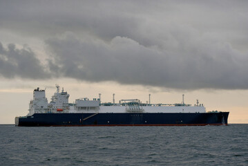 Naklejka premium LNG Carrier, Liquefied Natural Gas Tanker With Offshore Wind Turbines Generators On Horizon