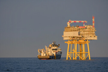 Offshore Substation Platform and SOV Vessel in DP Mode, Wind Farm Construction Site During Golden...