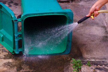 Cleaning the trash can with a water hose