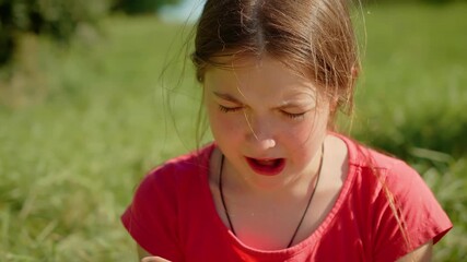Young girl eating sour lemon, making expressive face. Kid tasting tart lemon outdoors, reacting strongly to sourness. Child biting into lemon slice, showing exaggerated sour reaction in sunny