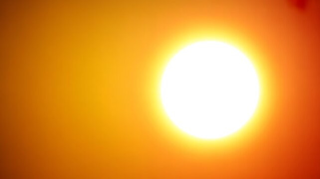 Bright glowing sun with halo effect against gradient orange background capturing radiant solar energy