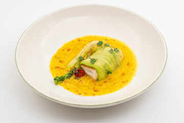 Zucchini-wrapped fish fillet in saffron-infused yellow sauce