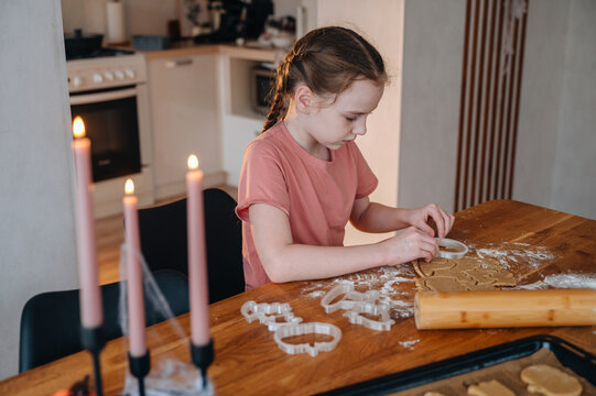 Girl baking halloween cookies at home in kitchen