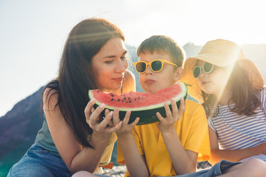 Family enjoying a watermelon on a sunny day