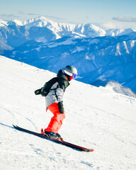 Young skier wearing helmet skiing downhill on snowy mountain, dynamic outdoor winter sports action