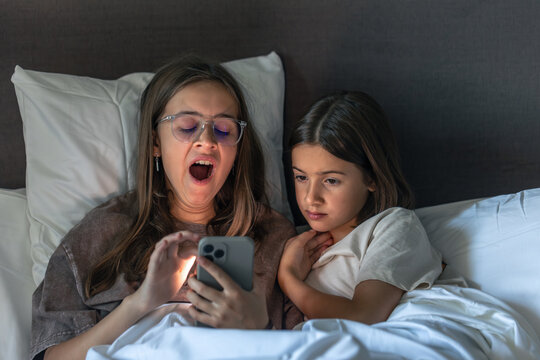 Late smartphone screen. Yawn and fatigue. Home evening