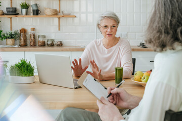 Mature nutritionist guiding client sitting at home