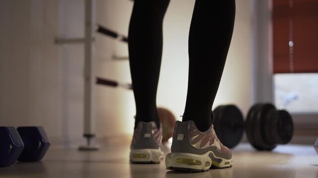 A man in sneakers takes a few steps forward toward the dumbbells