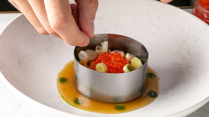 A culinary artisan's hand meticulously garnishes avant-garde dish, celebrating molecular gastronomy...