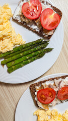 Rustic rye breakfast delight with radiant tomatoes, creamy eggs, and verdant asparagus, evoking Oktoberfest brunch or Scandinavian Midsummer