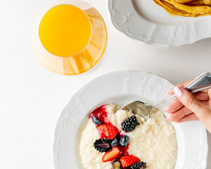 A delicate symphony of berries adorns silky rice pudding beside radiant orange juice, invoking Solstice dawn and Hygge comfort