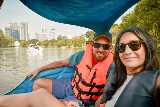 Happy young caucasian couple take selfie look at camera enjoy sport activity on pedal boat in famous public Lumphini park in summer. Bangkok relaxation leisure activities - Powered by Adobe