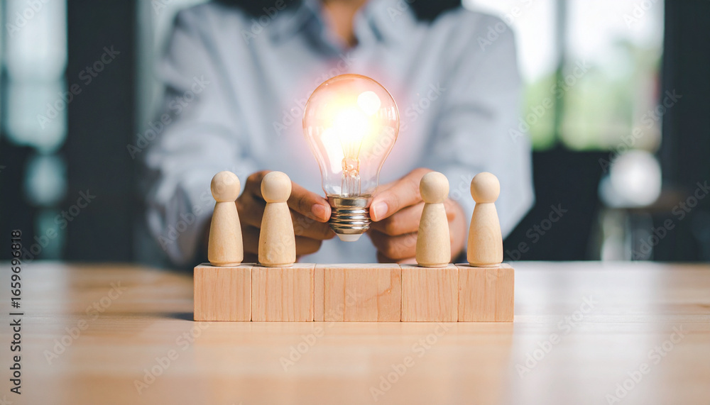 Poster an illuminated light bulb held in front of four figurines representing teamwork and ideas