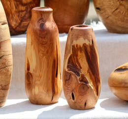 Two wooden vases with a brown finish sit on a table