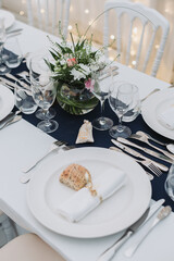Wedding table setting with bread roll, napkin, glassware and floral centerpiece